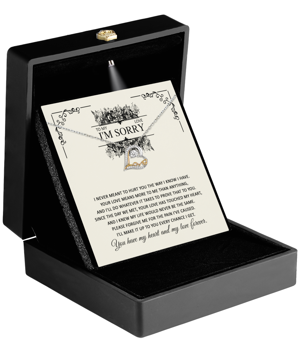 A "Sorry-Every Chance - Love Dancing Necklace" showcased in a black jewelry box with a spotlight illuminating its 14k gold heart pendant. The background features a note on ivory paper with illustrated roses, reading "To My Love, I'm Sorry," followed by an apology message and a vow of love.