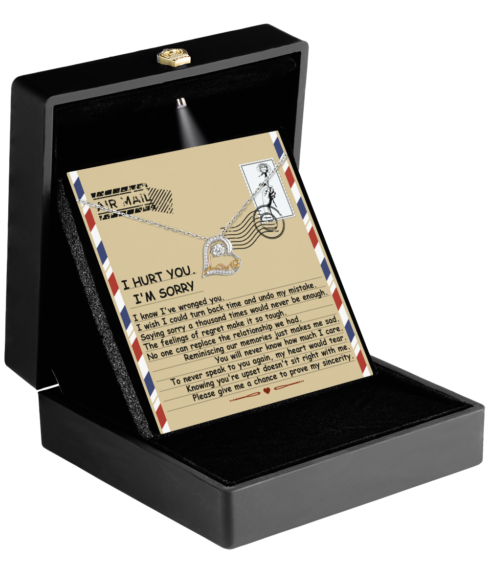 Inside a black jewelry box, the Sorry-Makes Me Sad - Love Dancing Necklace featuring a 14k gold heart pendant is cradled. Nestled within, a card showcases an illustrated letter expressing heartfelt regrets and maternal love.