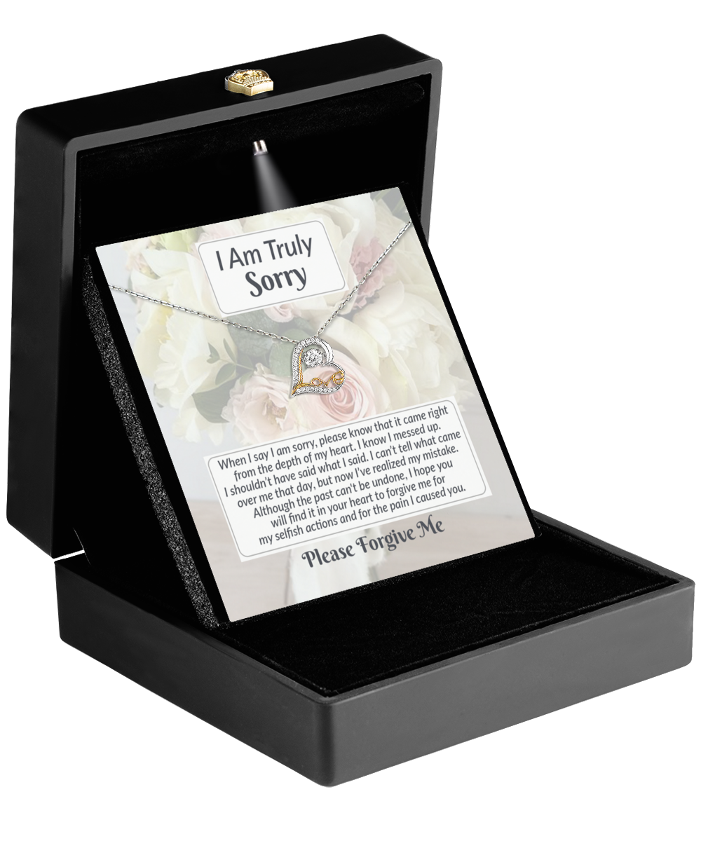 Open black jewelry box displaying a heartfelt "I Am Truly Sorry" card with an apology message and the stunning Sorry-What I Said - Love Dancing Necklace featuring a heart pendant.