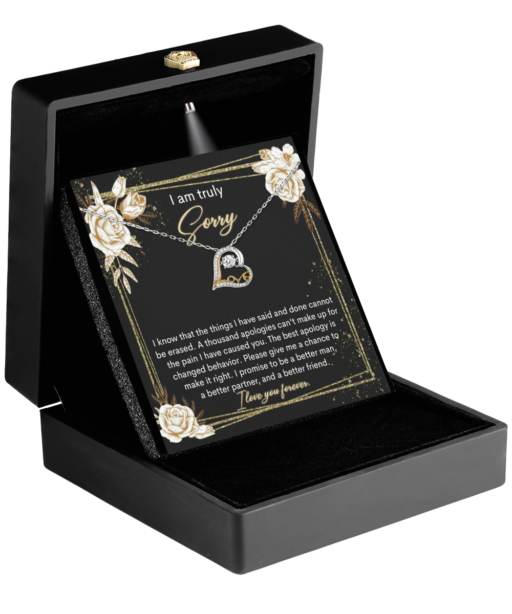 Open black jewelry box showcasing a Sorry-Cannot Be Erased - Love Dancing Necklace with a heart pendant. Inside the lid, an apology and love message is displayed, adorned with delicate rose illustrations.