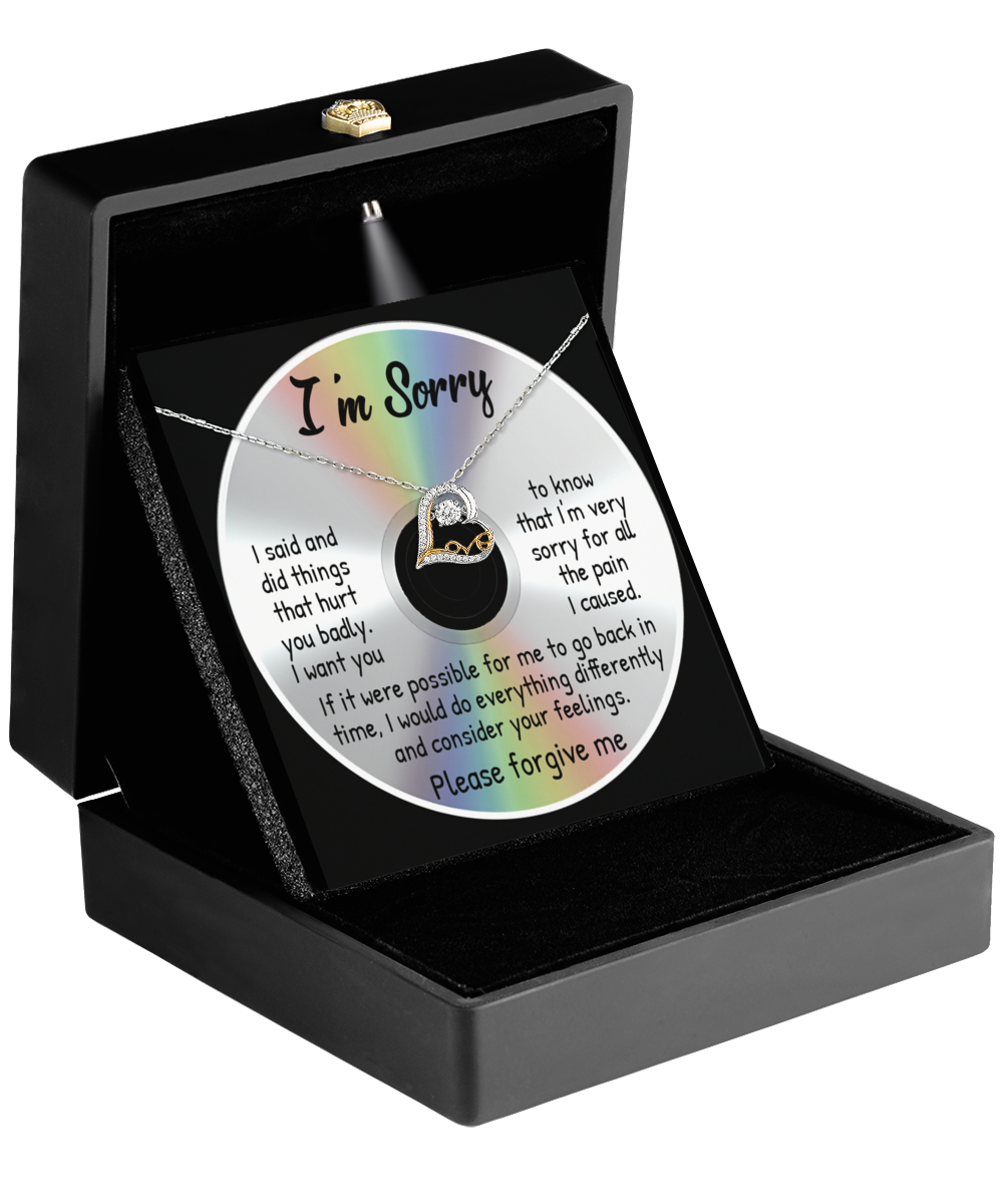 An open black box holds a Sorry-Back In Time - Love Dancing Necklace made of sterling silver and a CD featuring an apology message. The CD, with "I'm Sorry" written on it, contains a heartfelt apology presented in colorful text.