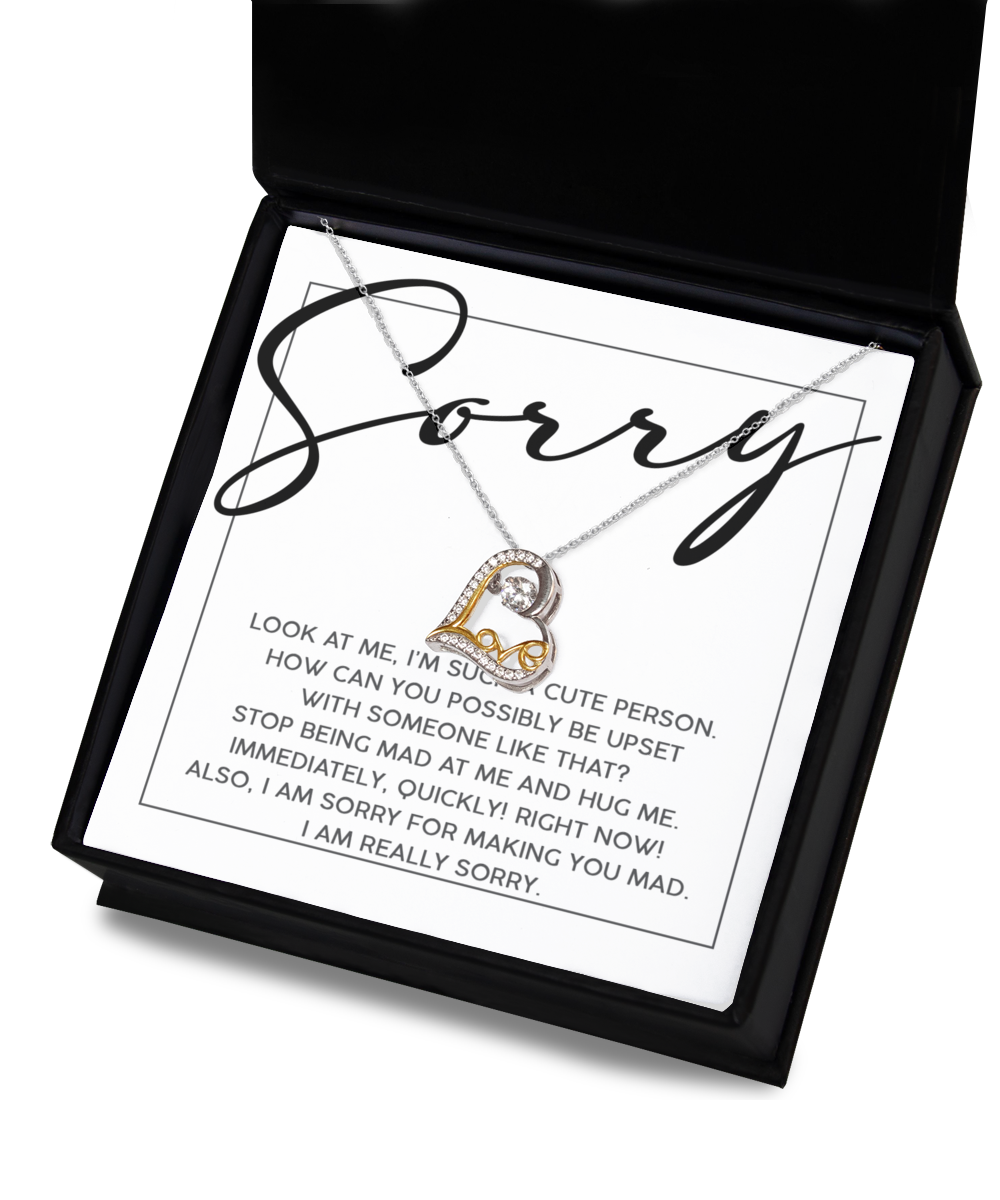 Open box with a "Sorry-Someone Like That - Love Dancing Necklace." A 14k Gold heart and crystal necklace inside, featuring a humorous apology note starting with "Sorry," captures the playful charm of maternal love.