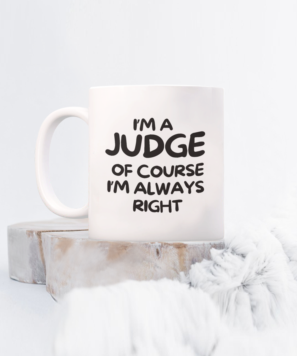 The "I'm A Judge Of Course I'm Always Right" Coffee Mug features bold black text on white, displayed on wooden blocks with a fur blanket nearby. It's printed and shipped from the USA and is available for a limited time.