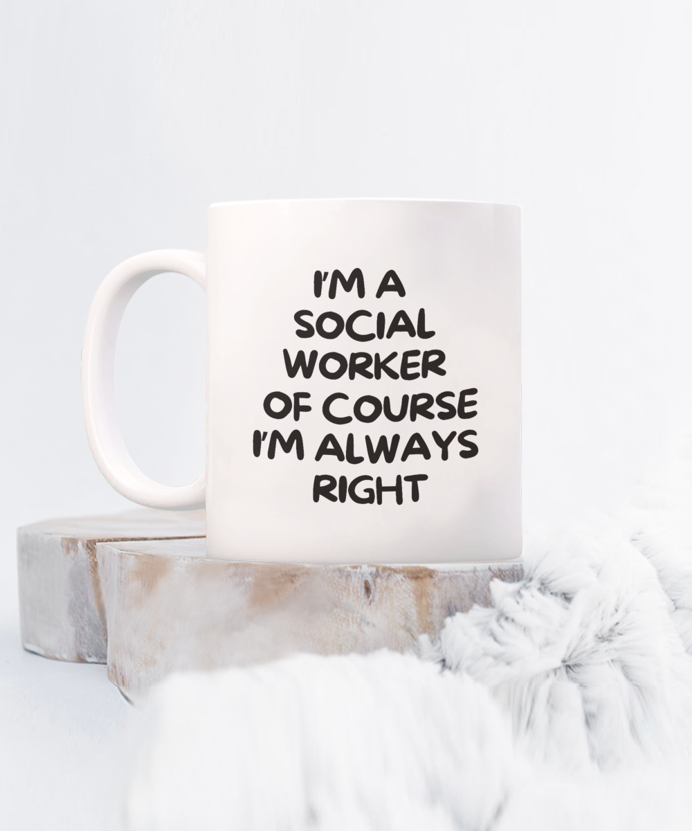 The "I'm A Social Worker Of Course I'm Always Right" white mug, featuring black text, is set on a wooden surface with soft fabric in the foreground. This exclusive item is printed and shipped from the USA and unavailable in stores. Limited-time offer!.