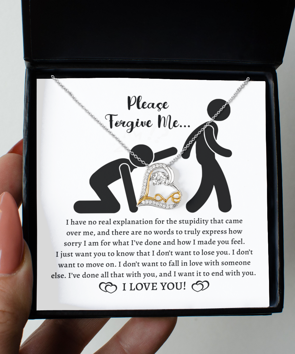 The Sorry-Made You Feel - Love Dancing Necklace, a stunning 14k gold piece with a heart pendant, rests elegantly on top of a card in an open box. The card features a heartfelt apology message accompanied by an illustration of one person kneeling and chained to another.