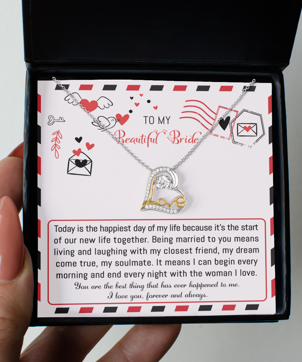 The "To Bride-The Happiest Day - Love Dancing Necklace," available in sterling silver or 14k gold for timeless elegance, comes with a card that delivers a romantic message to "my beautiful bride" about love, happiness, and a shared future. This heart-shaped necklace is elegantly presented inside a black jewelry box.