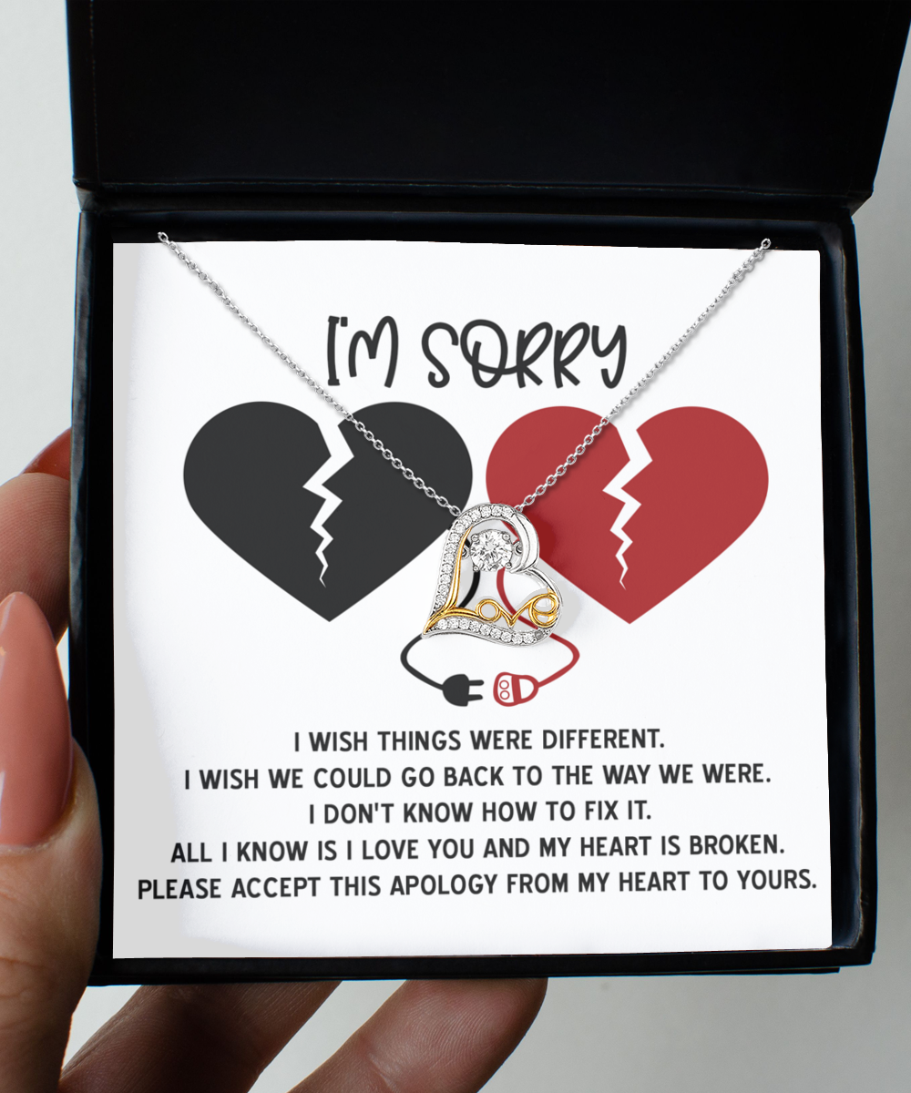 The Sorry-Heart Is Broken - Love Dancing Necklace is a sterling silver piece featuring intertwined hearts on a display card that reads, "I'm sorry" above two broken hearts. The text below conveys regret and hopes for reconciliation. Adorned with delicate Cubic Zirconia accents, this necklace serves as a truly heartfelt apology gift.