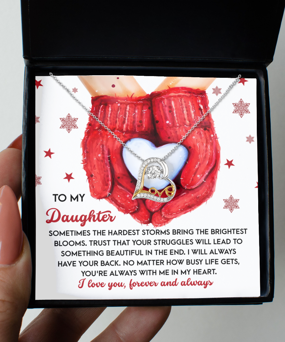 The Daughter-In My Heart - Love Dancing Necklace is an ideal gift to express maternal love, presented in a black box with a heartwarming card featuring red mittens holding a white heart, symbolizing love and support for your daughter.