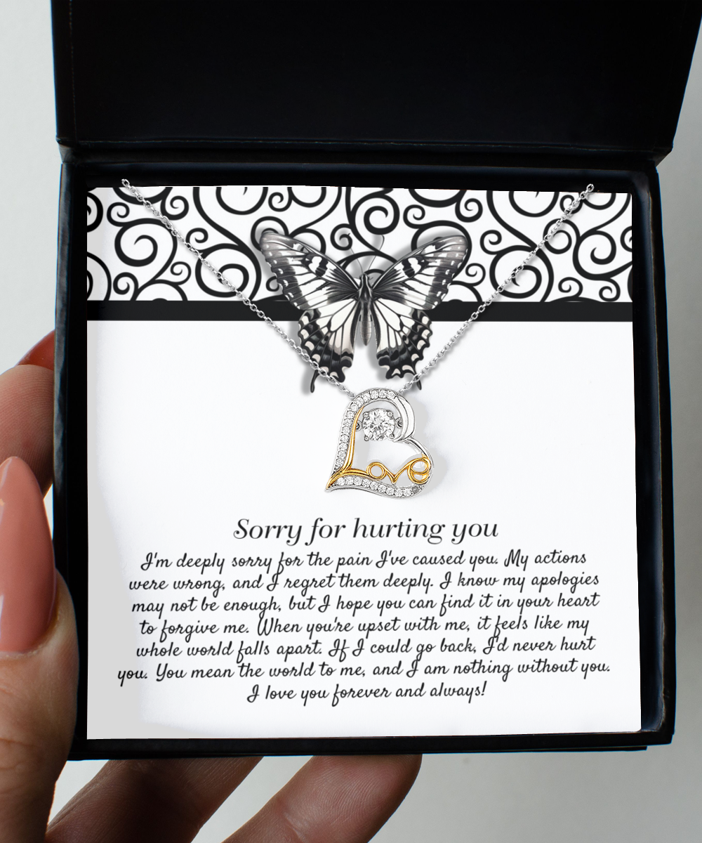 The Sorry-Nothing Without You - Love Dancing Necklace is a .925 sterling silver piece featuring a pendant of interlocking hearts. It is beautifully displayed on a card adorned with an apology message and a butterfly graphic, all elegantly packaged in a black box. The text on the card conveys regret and love.