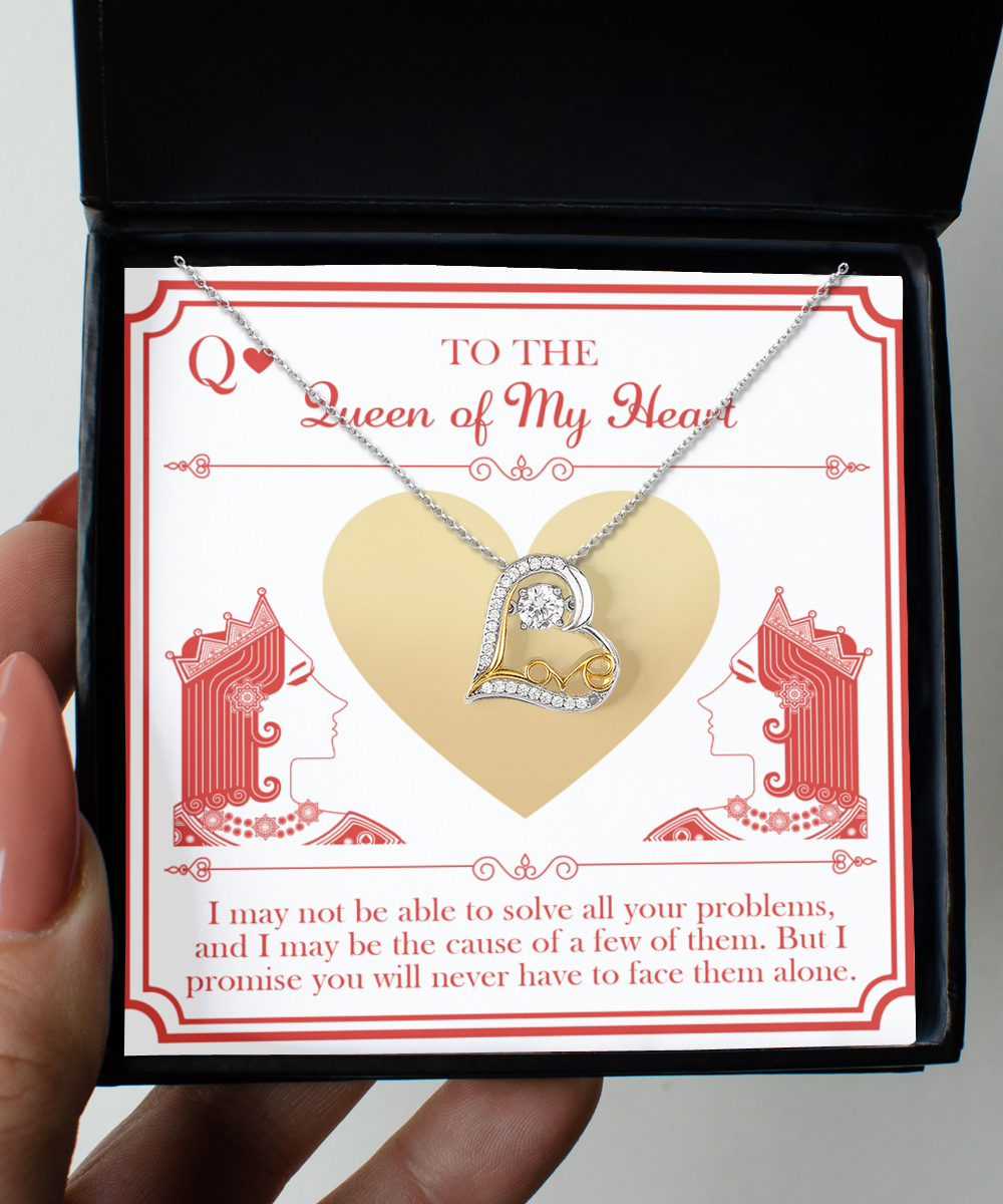 A hand holds an open jewelry box displaying the "To Wife-The Queen - Love Dancing Necklace," a heart-shaped, sterling silver piece adorned with small diamonds. Behind the necklace is a card featuring illustrations of two queens in profile and a message: "To the Queen of My Heart." The background showcases red and gold accents.