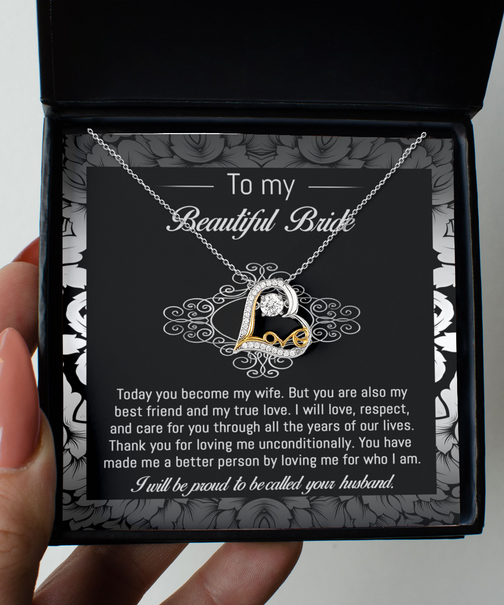 A 14k gold "To Bride-My True Love - Love Dancing Necklace" with a heart-shaped pendant rests in a black and white box. The inside of the box lid has a message addressed to a bride from her husband, expressing love and commitment.