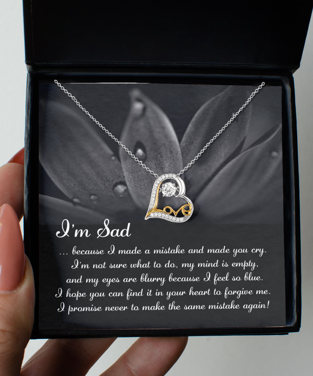 The "Sorry-Feel So Blue - Love Dancing Necklace," a heart-shaped pendant crafted with genuine .925 Sterling Silver and AAAA Cubic Zirconia, is displayed in an open box with a message that reads: "I'm Sad...because I made a mistake and made you cry... I promise never to make the same mistake again.