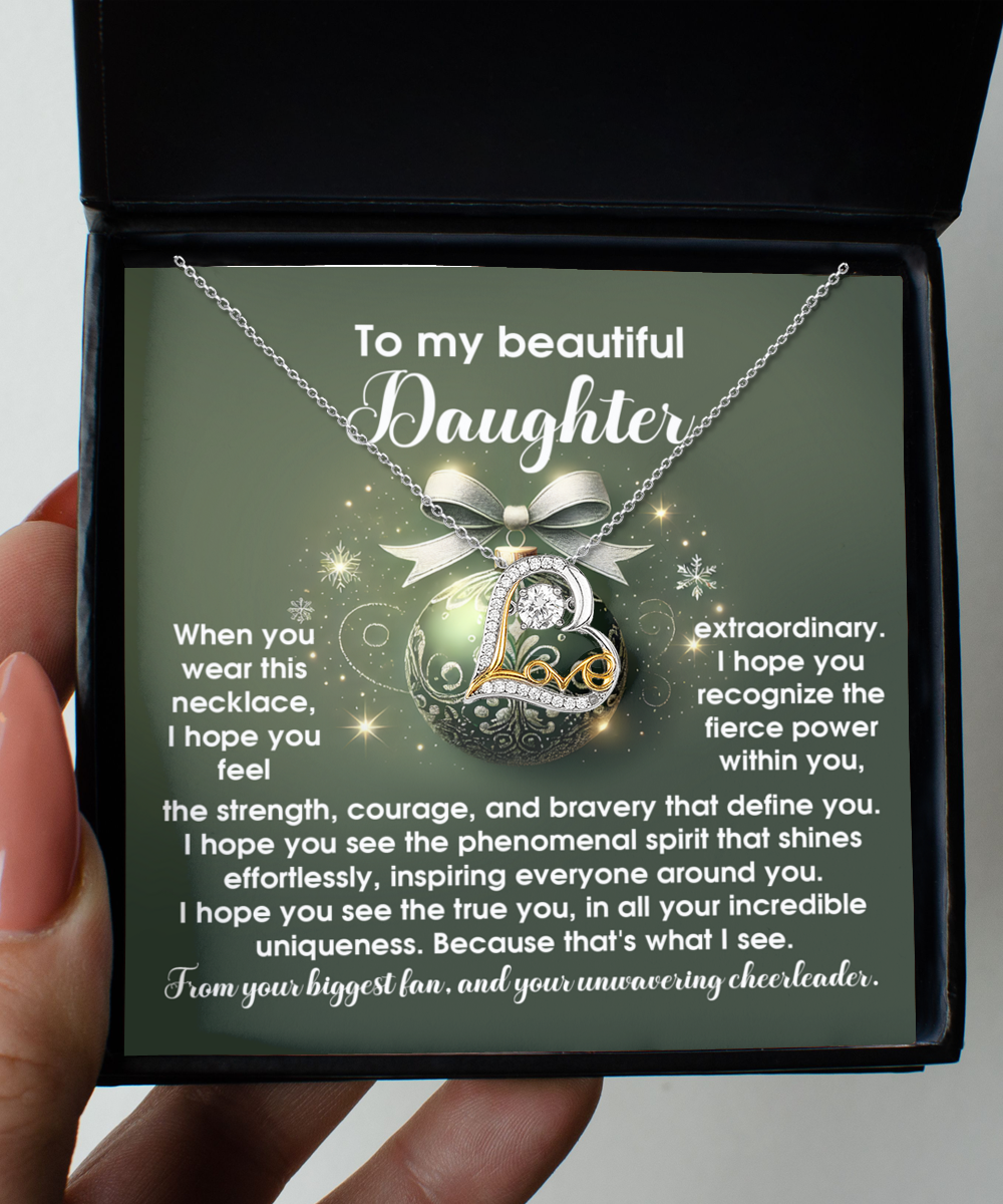 A hand holds an open box showcasing the beautiful Daughter-Get Back Up - Love Dancing Necklace. Within the lid, an inspirational message is addressed to a daughter, expressing love and encouragement, perfectly enhancing the rhodium-plated elegance of this heartfelt gift.