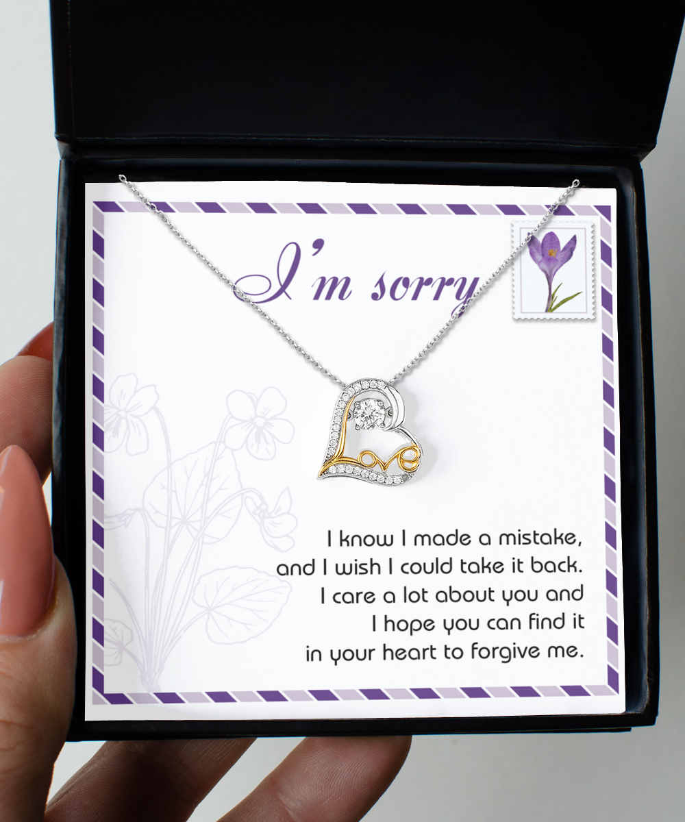 The Sorry-Take It Back - Love Dancing Necklace, a sterling silver and 14k gold heart-shaped piece, is displayed with a card that says "I'm sorry" above an apology message in a decorative box.