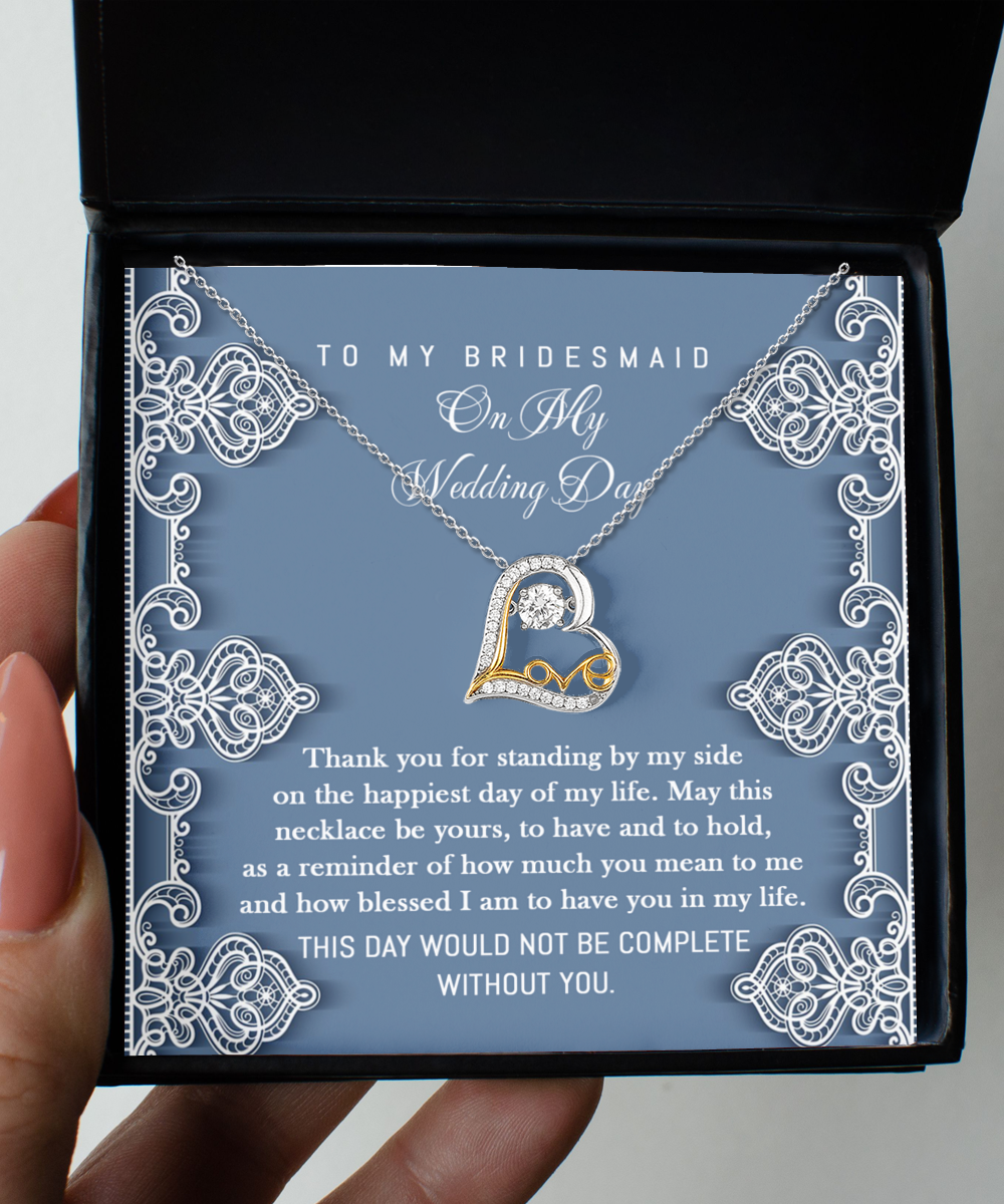 A Bridesmaid-By My Side - Love Dancing Necklace with a heart-shaped pendant, crafted from 14k gold, inside a box with a message expressing gratitude to a bridesmaid for her support on the wedding day.