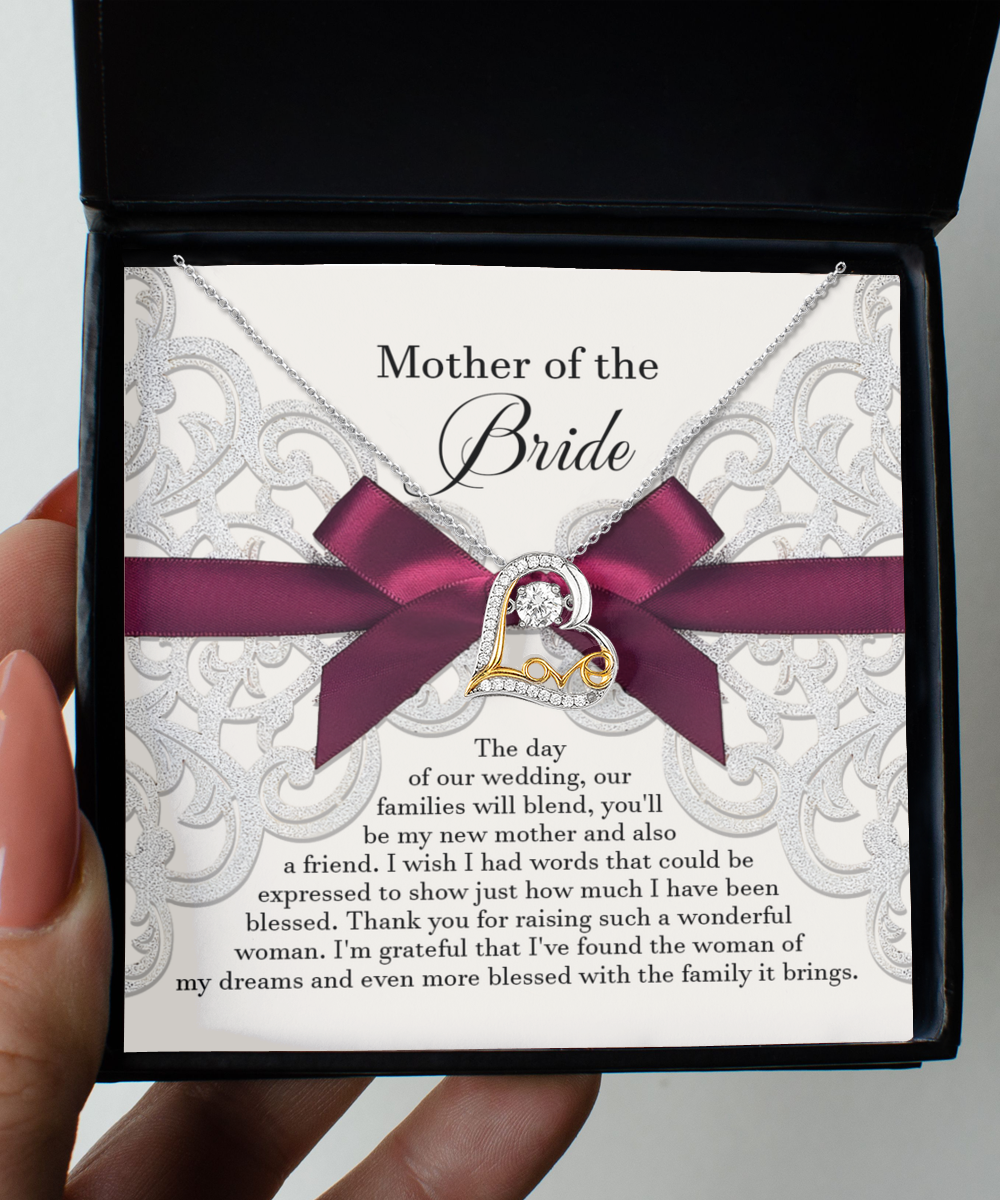 A "To Bride's Mom, My New Mother - Love Dancing Necklace" with a heart-shaped pendant on a silver chain. This handcrafted jewelry piece is beautifully displayed in a box, complete with a note expressing gratitude and love to the mother of the bride.