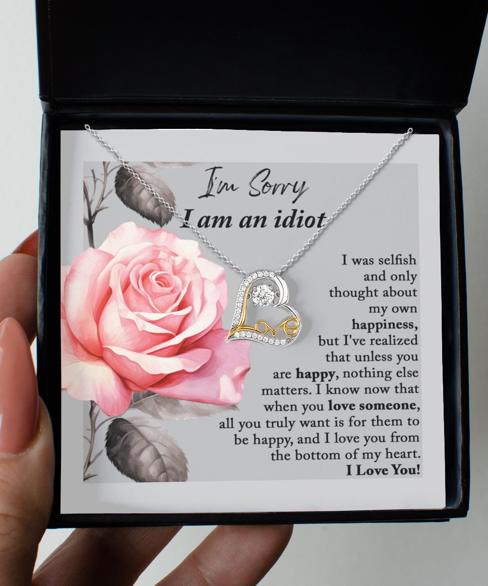 The Sorry-Love Someone - Love Dancing Necklace, crafted in sterling silver with a heart-shaped pendant, is elegantly displayed on a card featuring an image of a pink rose. The heartfelt message accompanying the necklace expresses regret for selfishness and underscores the significance of others' happiness.