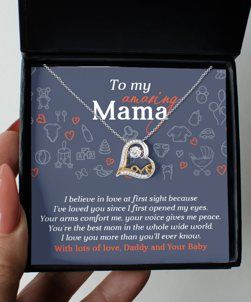 The "To Mom To Be, At First Sight - Love Dancing Necklace," crafted from 14k gold, features a heart-shaped pendant nestled in a jewelry box with a heartfelt message celebrating maternal love.