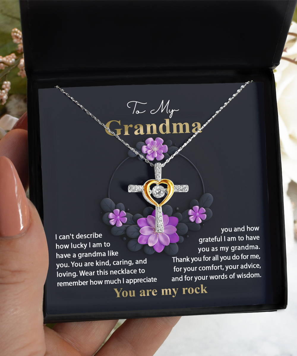 A hand holding a To Grandma, Words Of Wisdom - Cross Dancing Necklace by Gearbubble, presented in a box with a heartfelt message to a grandmother.