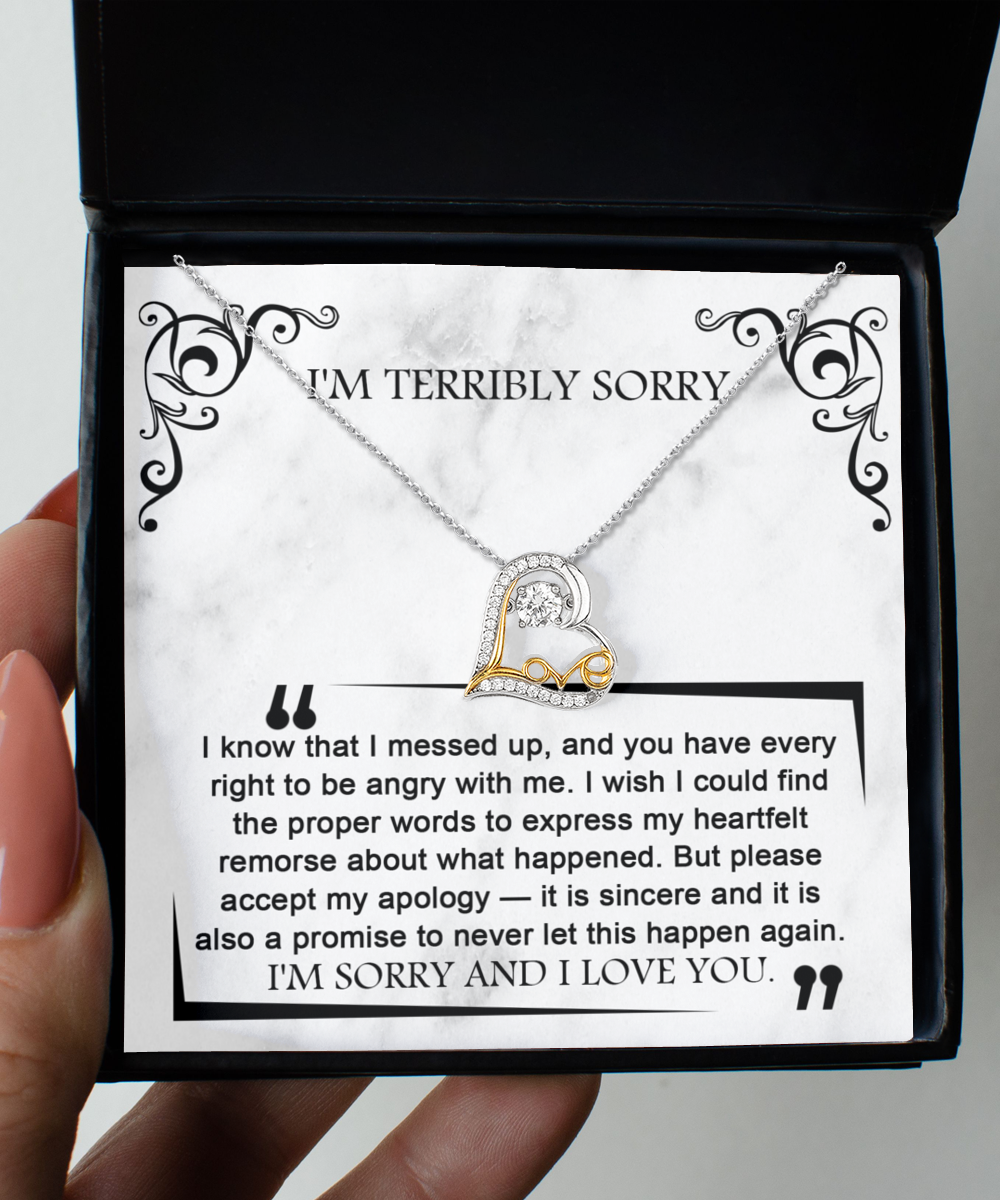 A hand holds an open box containing the "Sorry-Angry With Me - Love Dancing Necklace," a heart-shaped piece crafted in .925 Sterling Silver with a message saying "I'M TERRIBLY SORRY" and an apology note expressing regret and a promise to not repeat the mistake.