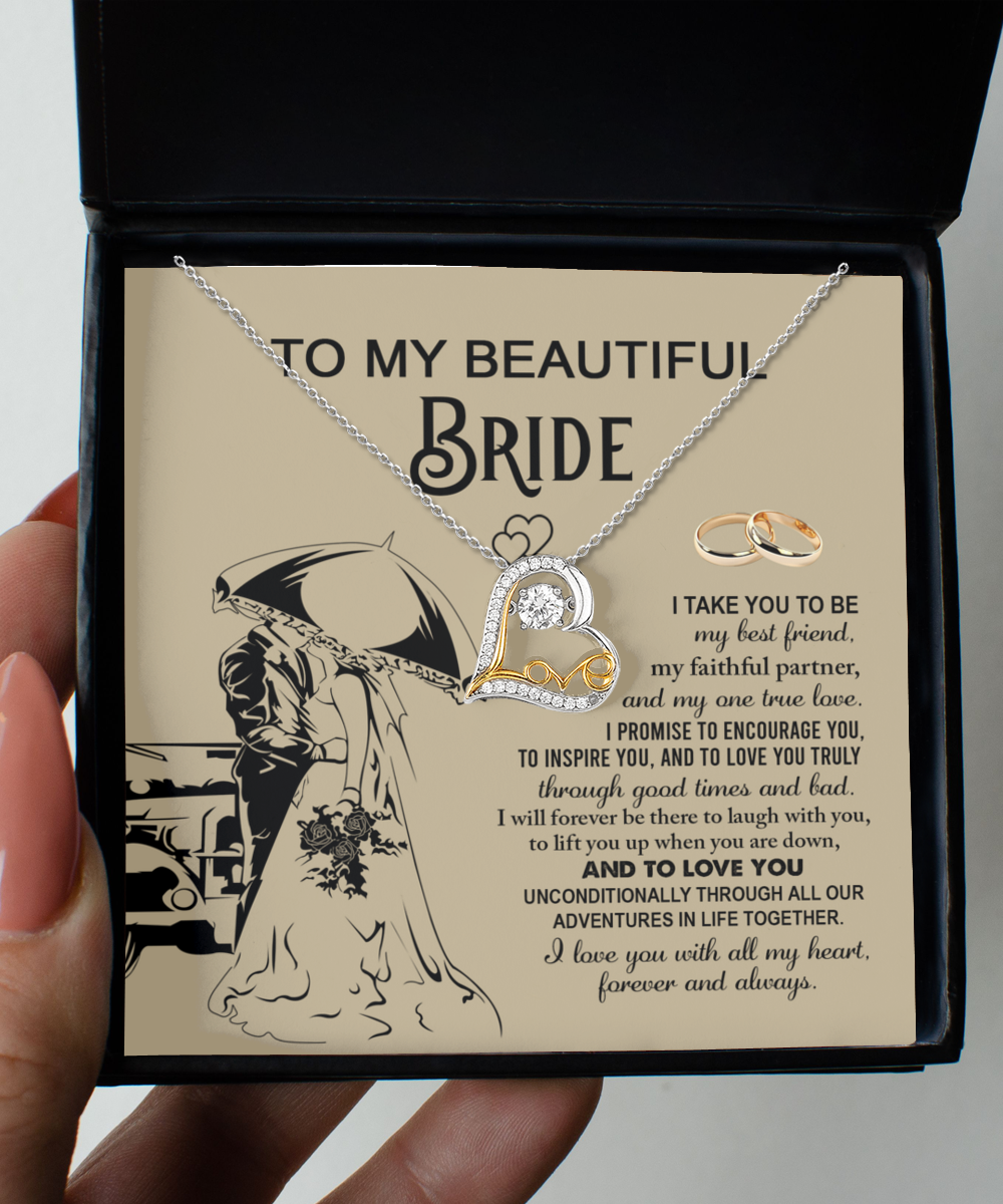 A sterling silver Bride-Faithful Partner - Love Dancing Necklace and two rings are elegantly displayed in a box with a heartfelt message for the bride, featuring vows of love, support, and encouragement. The illustration of a couple under an umbrella adds a romantic touch.