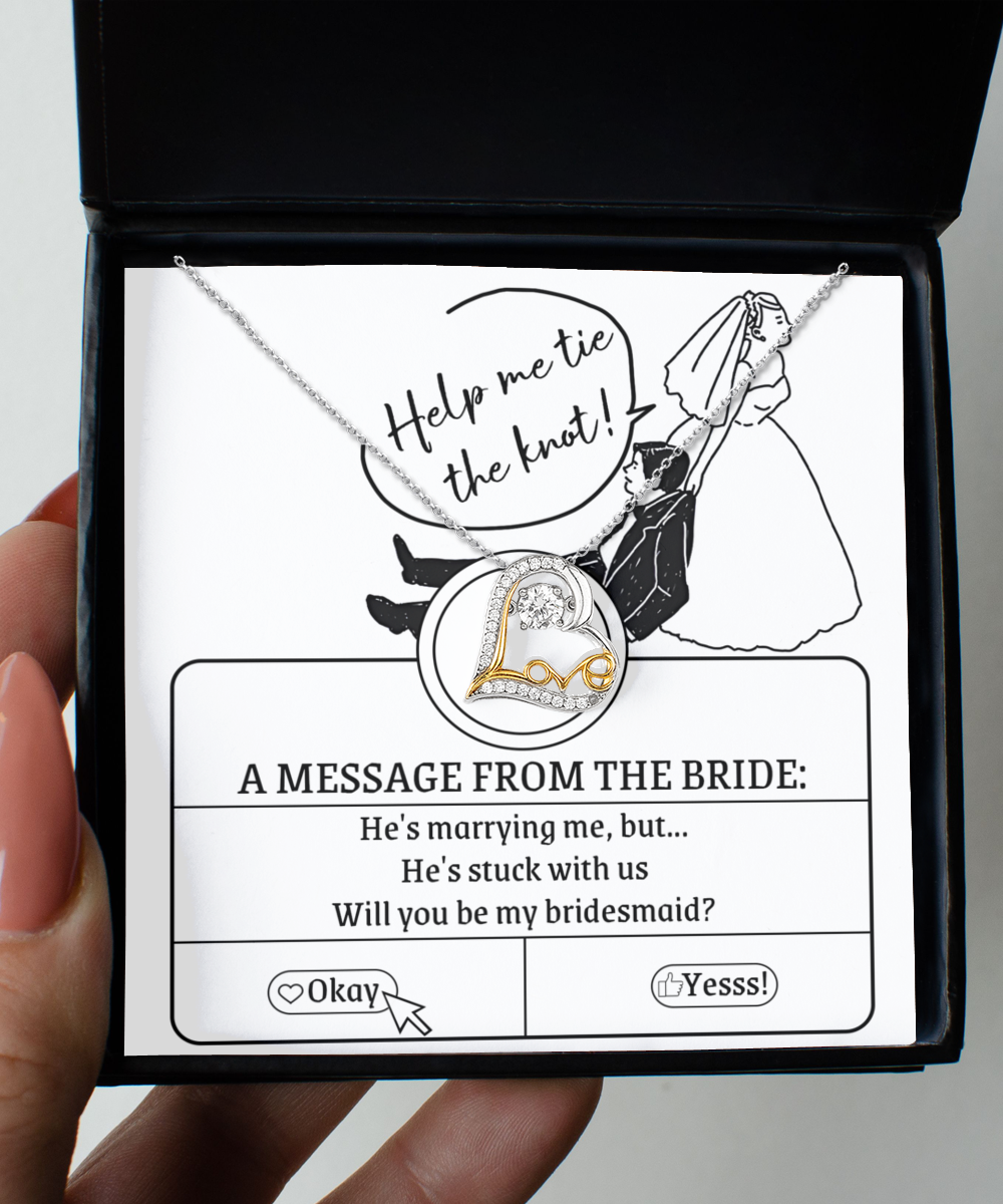 A Bridesmaid-Stuck With Us - Love Dancing Necklace with a 14k gold necklace inside. The box has an illustration of a bride pulling a groom with text: "He's marrying me, but... He's stuck with us. Will you be my bridesmaid?" and options "Okay" and "Yesss!".