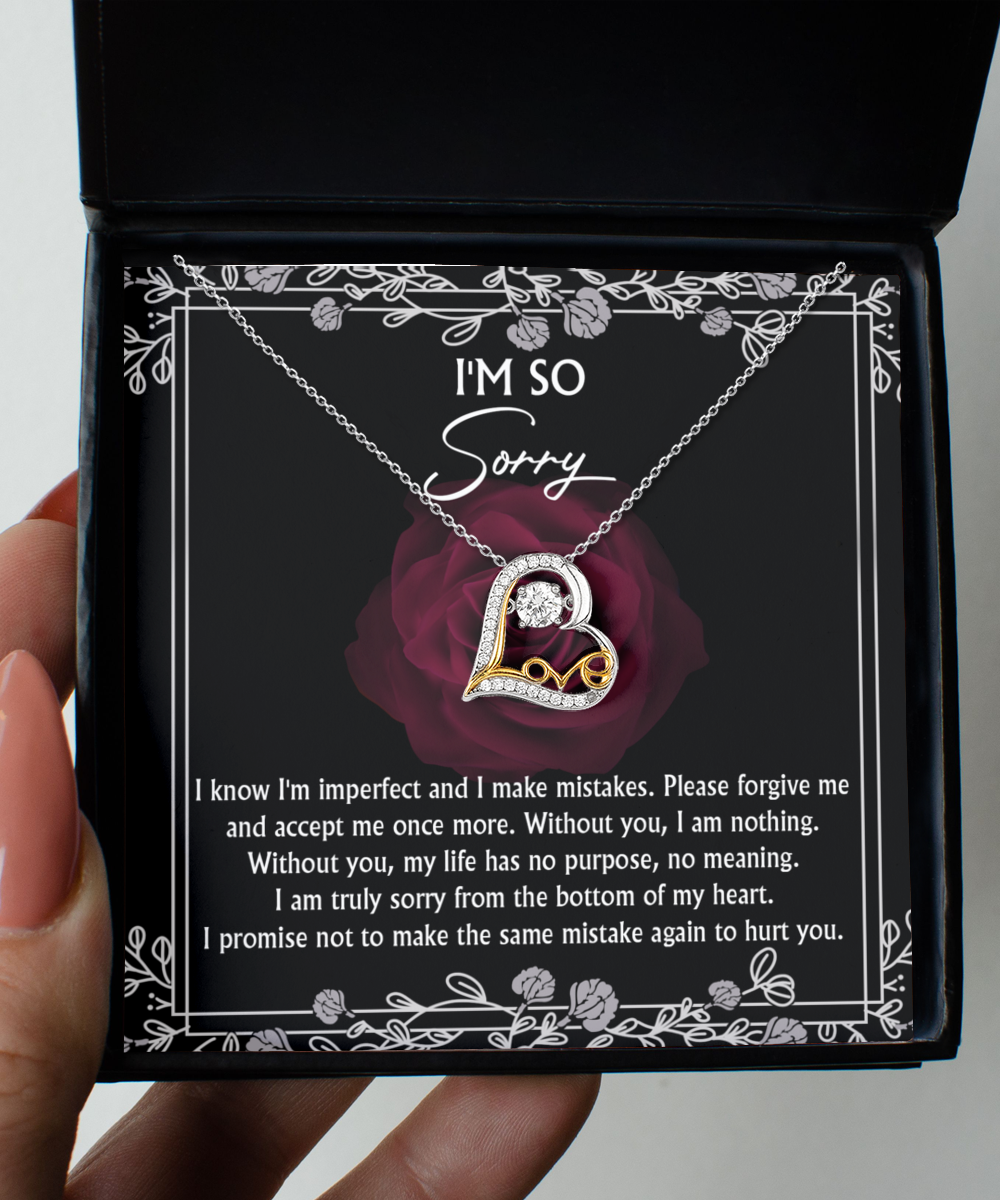 The Sorry-I Am Nothing - Love Dancing Necklace, a sterling silver heart-shaped pendant with a 14k gold accent and diamond, is presented in a box featuring an apology message printed on the inside lid and a dark rose design in the background.