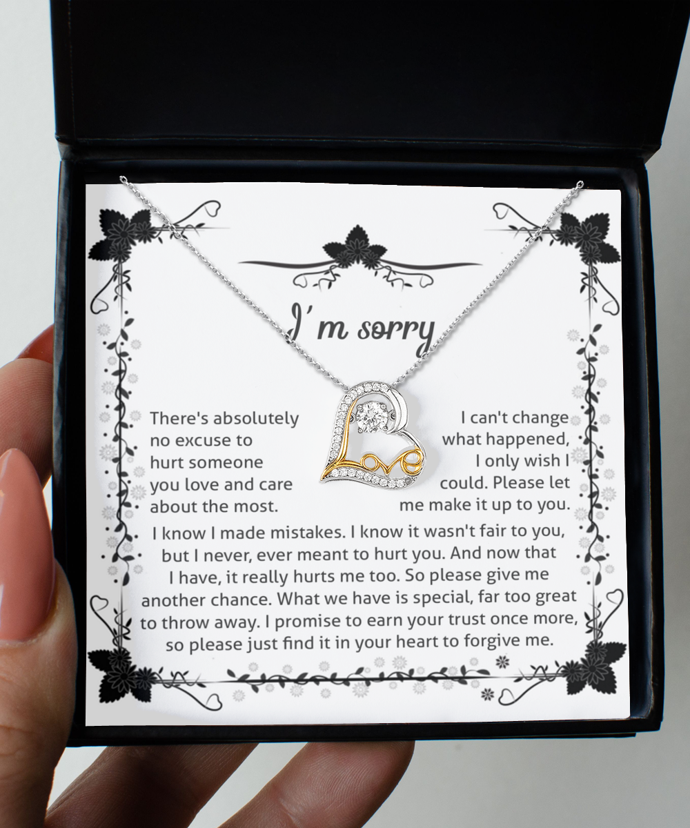 A hand holds an open gift box containing the "Sorry-No Excuse - Love Dancing Necklace," a sterling silver necklace featuring a heart pendant adorned with small diamonds and an infinity symbol. Inside the box, a heartfelt apology message is printed on a decorative card, expressing regret and a plea for forgiveness.