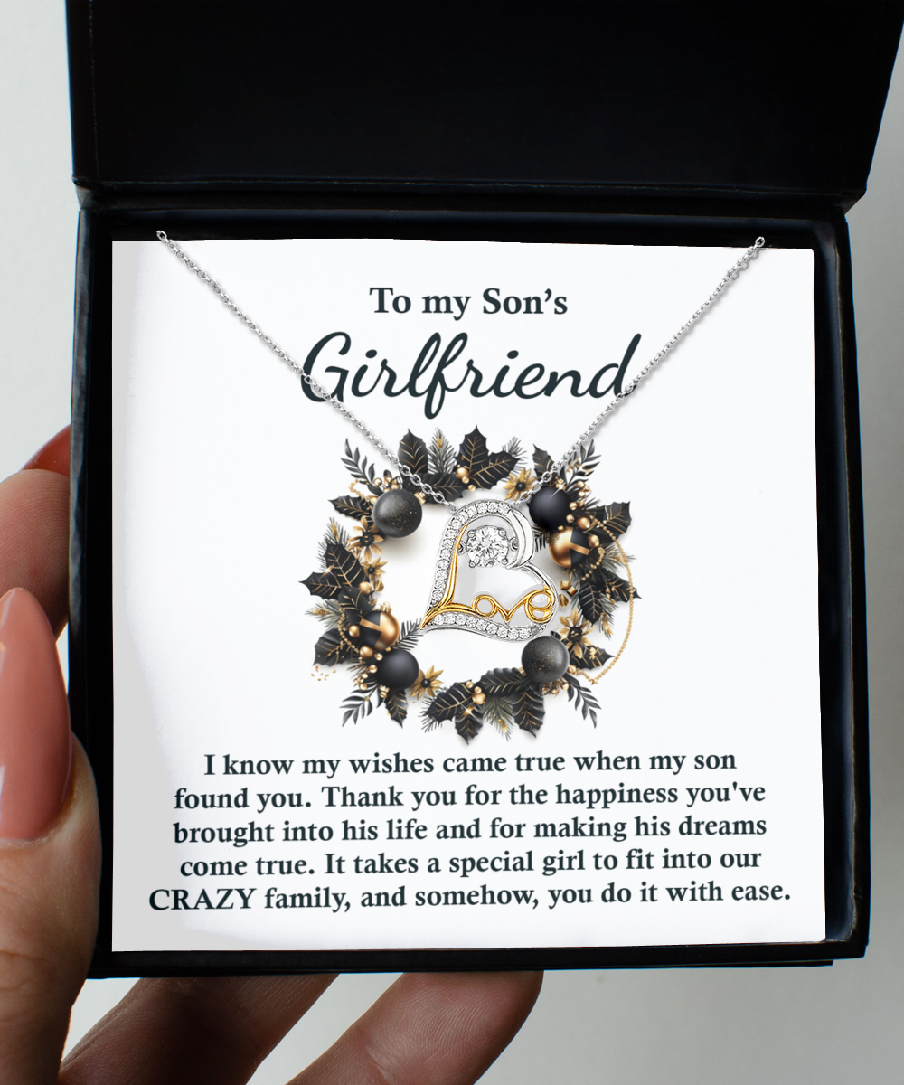 A box containing the "Son's Girlfriend- Found You - Love Dancing Necklace" in .925 Sterling Silver, showcasing a wreath design with a heart in the center. The accompanying card says, "To my Son's Girlfriend," followed by a heartfelt message.