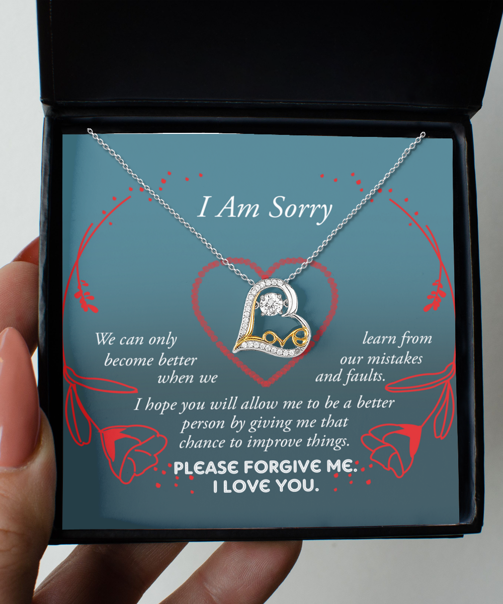 The "Sorry-Mistakes And Faults - Love Dancing Necklace" features an intertwined heart pendant, expertly crafted in .925 Sterling Silver. It is presented on a card reading "I Am Sorry," which includes a heartfelt apology message emphasizing growth and the pursuit of forgiveness, adorned with elegant red rose graphics.