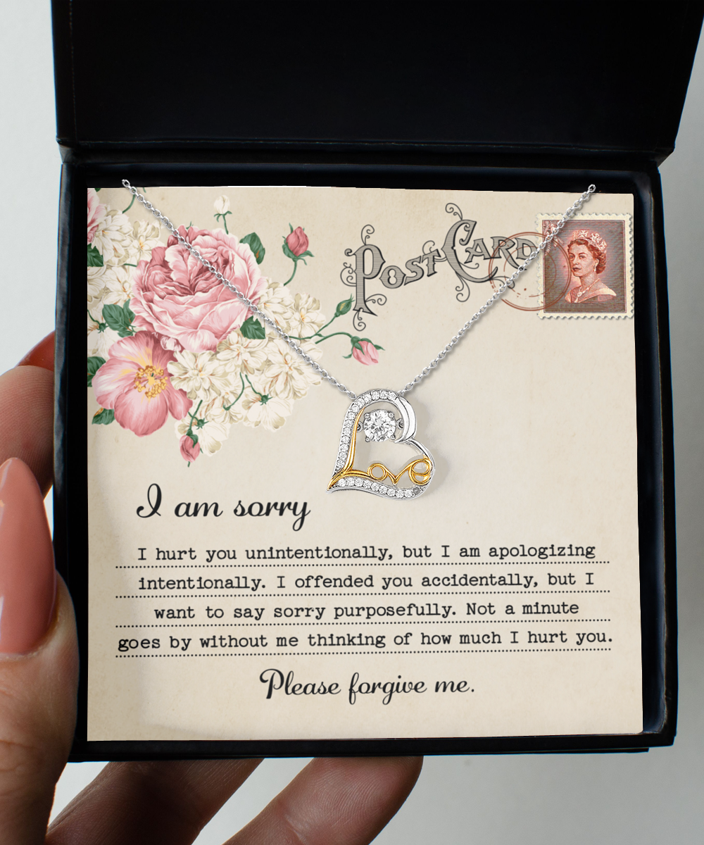 The Sorry-Apologizing Intentionally - Love Dancing Necklace features a 14k gold chain in a box, accompanied by a card that reads, "I am sorry. Please forgive me," adorned with decorative flowers and a vintage stamp depicting a woman's portrait.