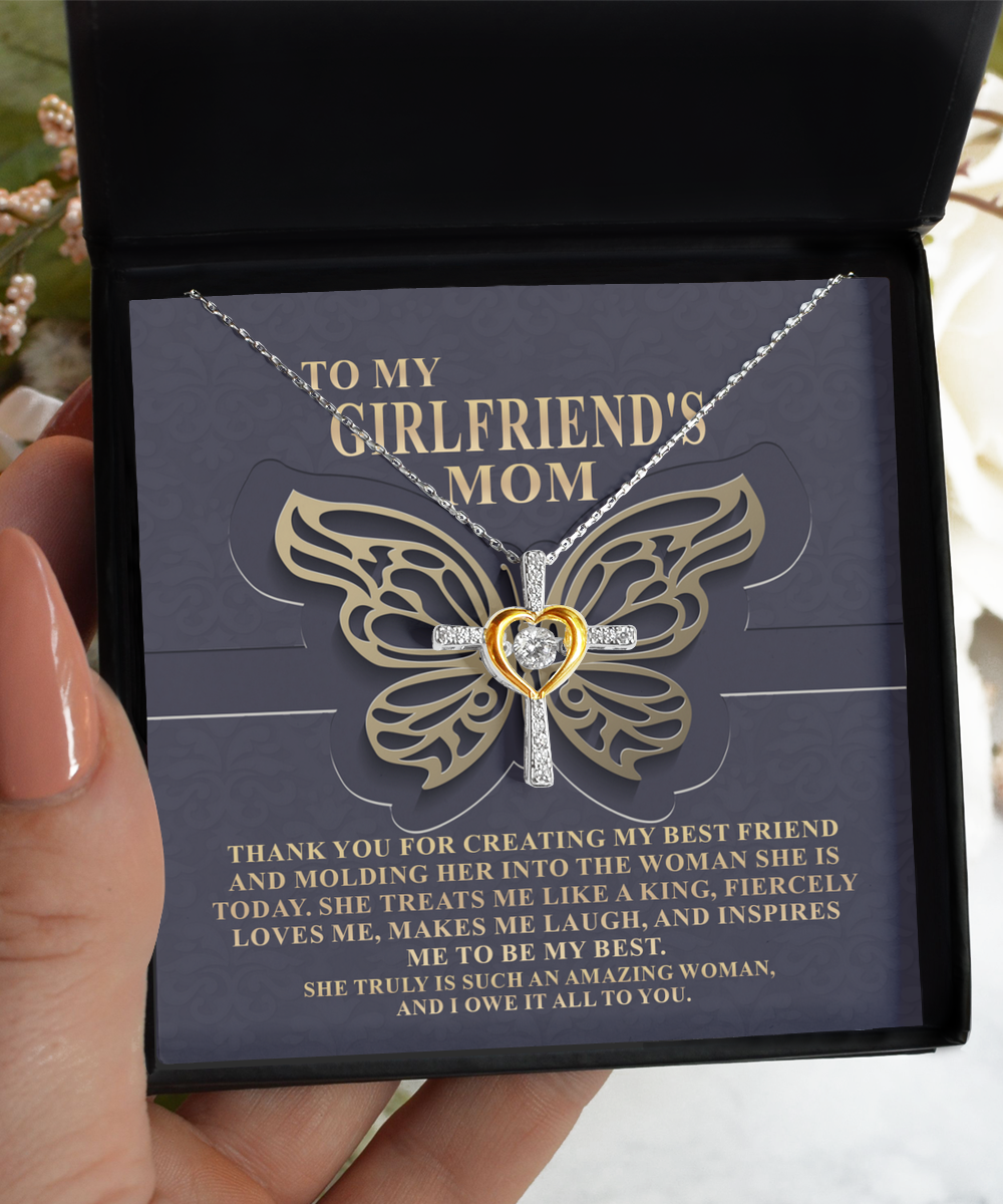 A person holds an open jewelry box presenting a butterfly-shaped, 14k gold plated necklace with an inscription thanking their girlfriend's mother. The product is the "To Girlfriend's Mom, Be My Best - Cross Dancing Necklace" by Gearbubble.