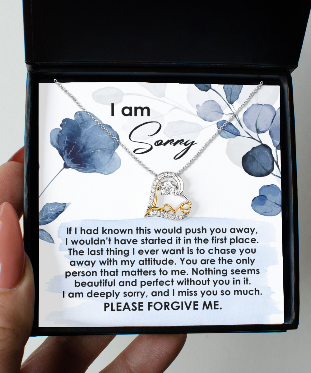 A hand holds an open box containing a "Sorry-Push You Away - Love Dancing Necklace" and a printed apology note expressing regret and asking for forgiveness.