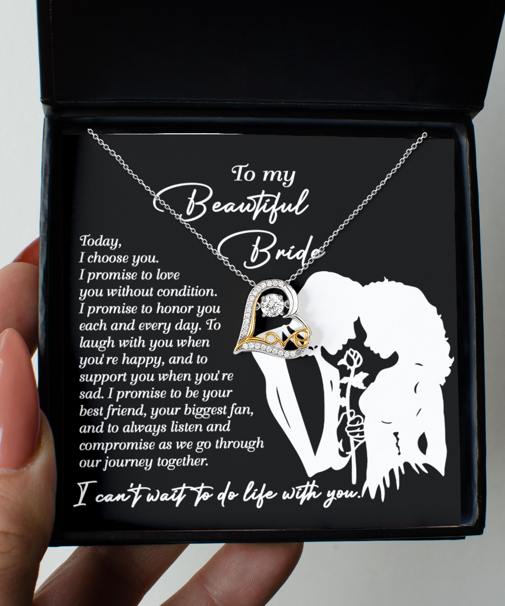 A Bride-I Choose You - Love Dancing Necklace featuring a heart and crystal pendant is displayed in a box. The lid showcases a silhouette of a couple, with text beginning "To my Beautiful Bride" followed by a romantic message. The pendant is available in Sterling Silver or 14k gold for an elegant touch.