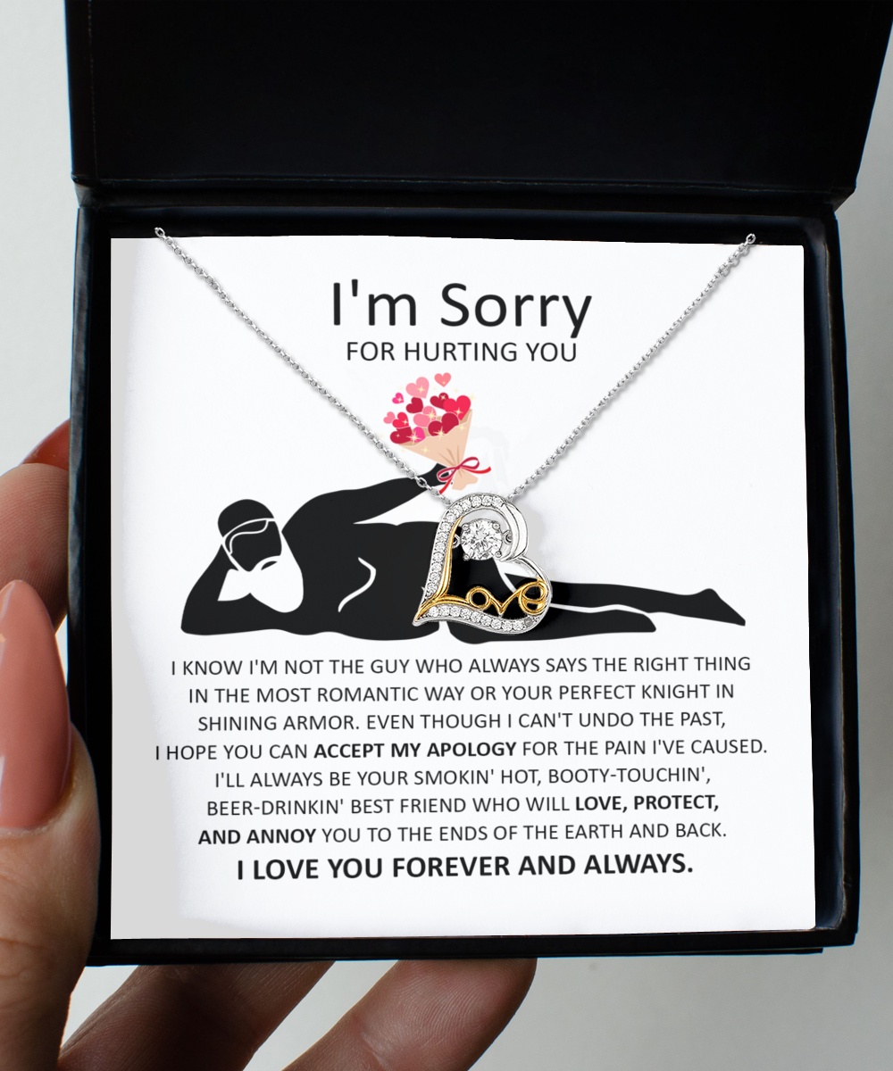 A 14k gold, heart-shaped "Love Dancing Necklace" from the "Sorry-The Most Romantic" collection is placed on a note of apology for causing hurt, featuring an illustration of a person resting and holding a bouquet, declaring everlasting love and protection.