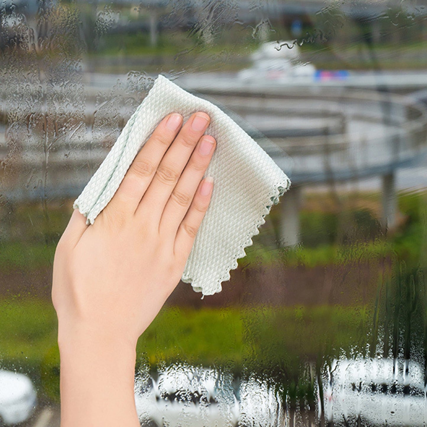 A person wiping a window with a Fish Scale Nano Reusable Cleaning Cloth from MezoJaoie Wonder Lifestyle Store.