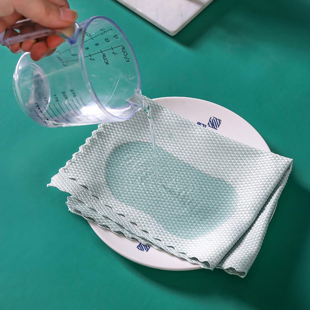 A person pouring water onto a glass using a Fish Scale Nano Reusable Cleaning Cloth from MezoJaoie Wonder Lifestyle Store, placed on a plate.