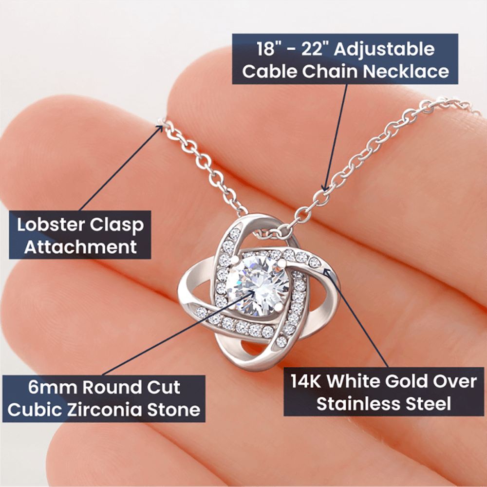A woman's hand is holding the ShineOn Fulfillment "The Moment We Met Love Knot Necklace - To Wife from Husband" with a diamond and a lobster clasp.
