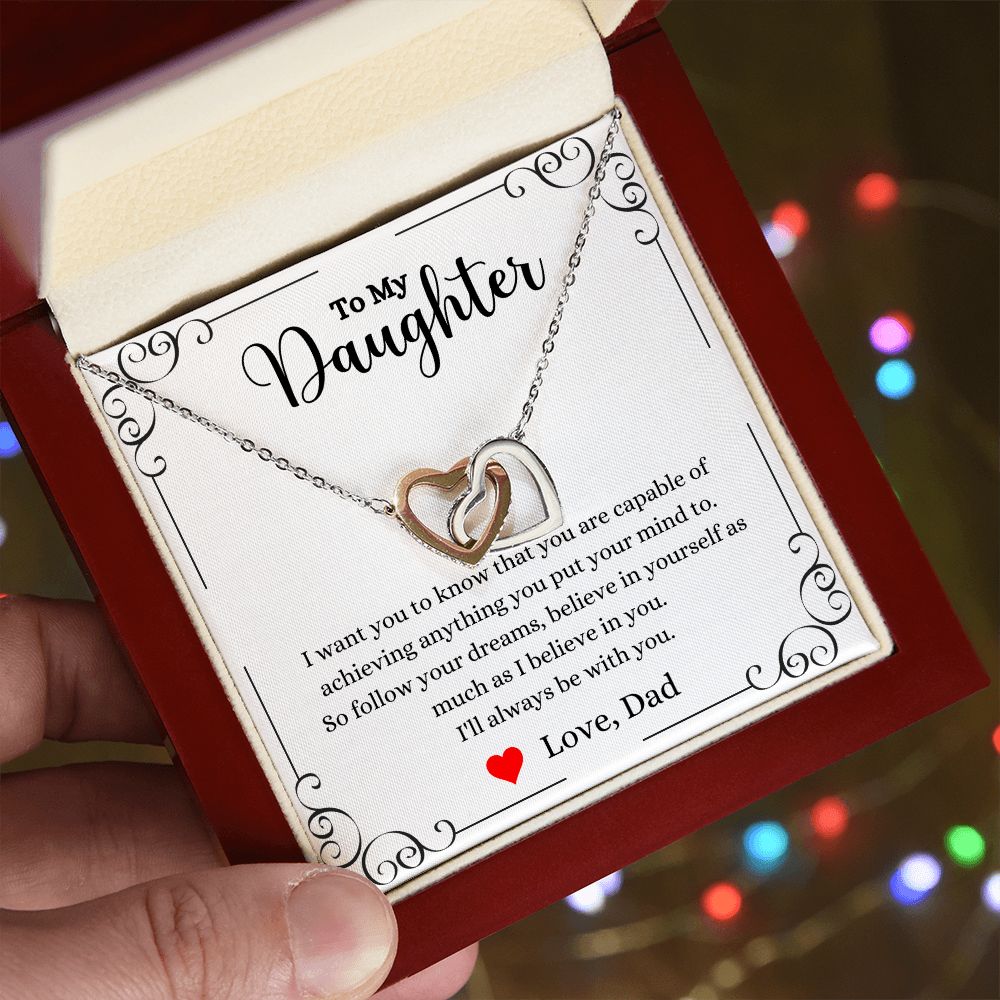 A person holding a ShineOn Fulfillment gift box with a Follow Your Dreams Interlocking Hearts Necklace - Gift for Daughter from Dad in it.