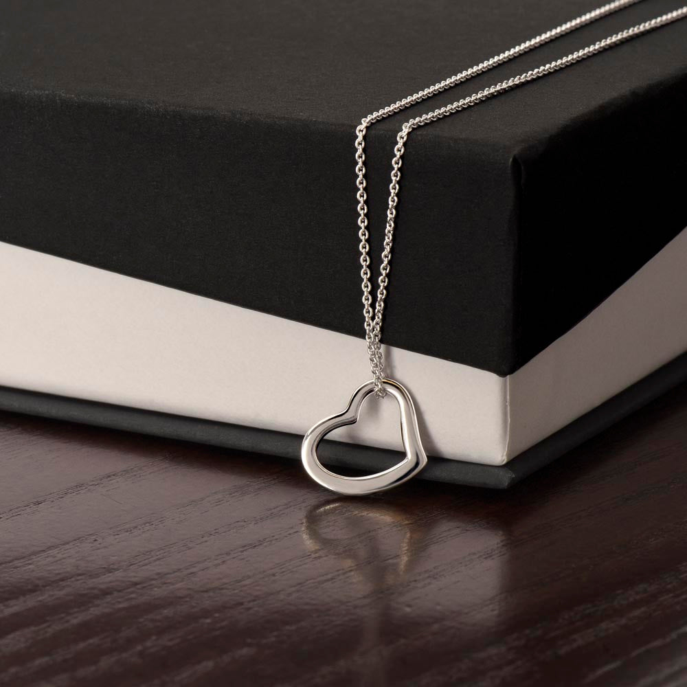 An I Wish You All The Abundance of Love - Delicate Heart Necklace For Daughter by ShineOn Fulfillment sits on top of a book.