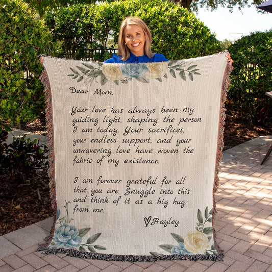 A mom holding up a Golden Value SG Personalized Note to Mom Heirloom Woven Blanket with a quote on it.