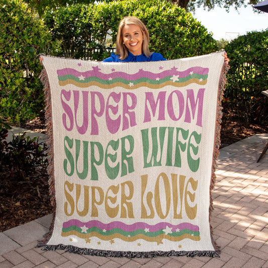 A woman proudly displays a Super Mom Super Wife Super Love Heirloom Woven Blanket by Golden Value SG.