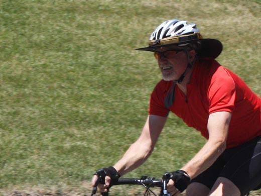 A man riding a road bike wearing Da Brim Sporty Cycling.